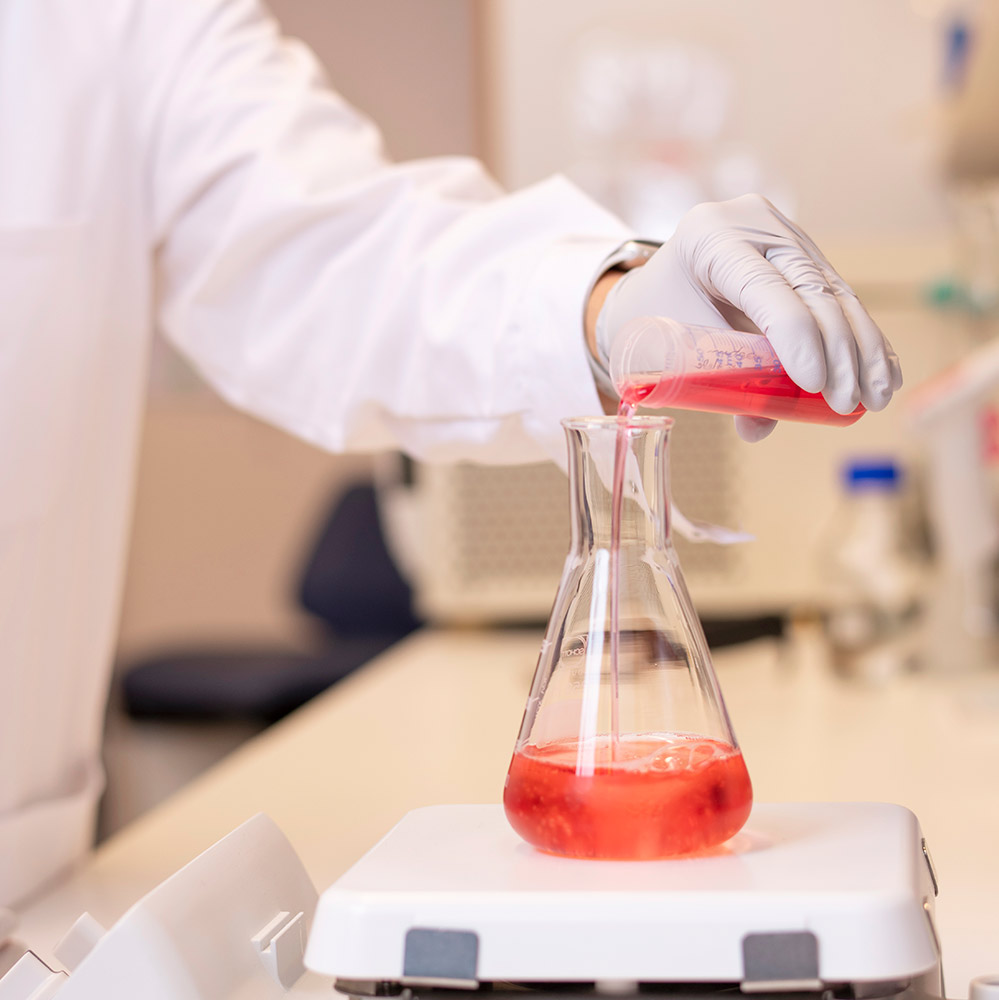 Person holding glass with red fluid